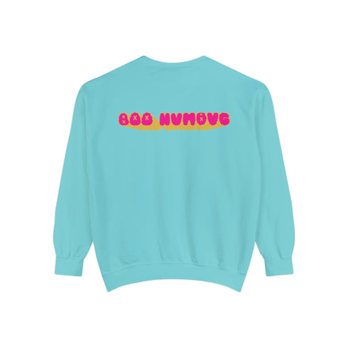 A holiday sweatshirt featuring a cute ghost character wearing a Santa hat, with two smaller ghosts on either side. Above them is the playful text "Boo Humbug," surrounded by snowflakes and festive elements. The design humorously combines spooky and festive themes for a unique holiday look.